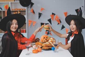 friendship, holiday and people concept - group of happy smiling friends in halloween costumes of vampire, devil, witch and cheetah at home party photo
