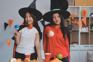 friendship, holiday and people concept - group of happy smiling friends in halloween costumes of vampire, devil, witch and cheetah at home party photo