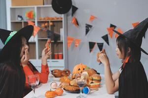 friendship, holiday and people concept - group of happy smiling friends in halloween costumes of vampire, devil, witch and cheetah at home party photo