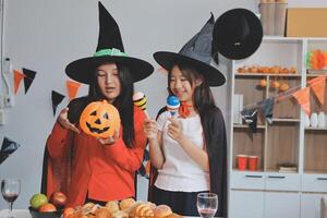 friendship, holiday and people concept - group of happy smiling friends in halloween costumes of vampire, devil, witch and cheetah at home party photo