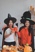 friendship, holiday and people concept - group of happy smiling friends in halloween costumes of vampire, devil, witch and cheetah at home party photo