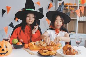 friendship, holiday and people concept - group of happy smiling friends in halloween costumes of vampire, devil, witch and cheetah at home party photo