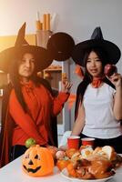 friendship, holiday and people concept - group of happy smiling friends in halloween costumes of vampire, devil, witch and cheetah at home party photo