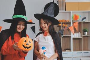 friendship, holiday and people concept - group of happy smiling friends in halloween costumes of vampire, devil, witch and cheetah at home party photo