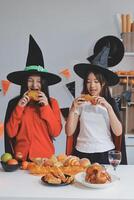 friendship, holiday and people concept - group of happy smiling friends in halloween costumes of vampire, devil, witch and cheetah at home party photo