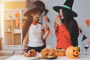friendship, holiday and people concept - group of happy smiling friends in halloween costumes of vampire, devil, witch and cheetah at home party photo