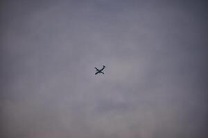Silhouette of an airplane flying in the middle of a white cloudy sky photo
