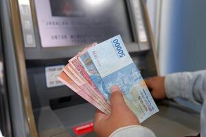 Cash withdrawal Indonesian rupiah money from automated teller machine photo