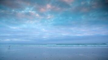 A person walking on the beach under a cloudy sky video