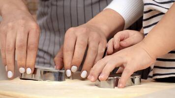 A parent and child are using cookie cutters to shape dough, enjoying quality time together in a warm kitchen. video