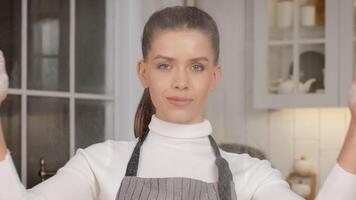 A woman is joyfully tossing flour in the air in a cheerful kitchen setting while baking. video