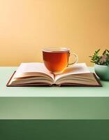 An open book with a cup of tea beside it isolated on minimalist background photo
