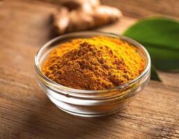 Turmeric spice in a glass container, on a natural wooden background photo