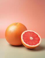 A whole grapefruit with a half cut beside it, on a pastel background photo