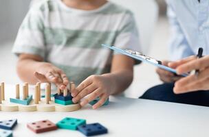 Kids development classes. Close up shot of unrecognizable little boy playing logical educational game during psychological consultation, specialist taking notes, empty space for text photo