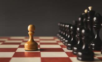 One pawn standing against set of black chess. Alone against many enemies, symbol of difficult fight or struggle, confidence concept photo