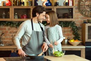 Family Time. Cute Little Girl Cooking Healthy Lunch With Dad In Kitchen, Bonding And Smiling, Touching Foreheads, Having Fun At Home, Enjoying Homemade Food, Using Organic Vegetables, Free Space photo