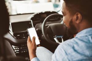 Afro Man Using Smartphone Sitting In New Car Buying Vehicle In Auto Center. Smart Driving App. Selective Focus, Mockup photo