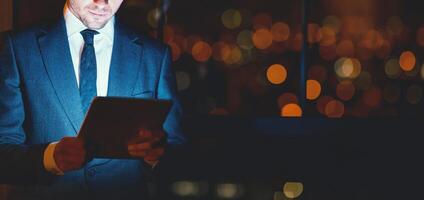 Unrecognizable Businessman Using Tablet Computer Working Standing In Modern Office At Night. Business Lifestyle. Cropped, Copy Space, Panorama photo