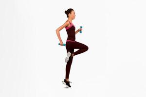 Workout. Happy Black Woman Jumping With Dumbbells Exercising In Studio On White Background. Full Length, Side View, Isolated photo