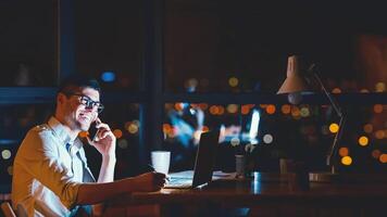 Happy Entrepreneur Guy Talking On Cellphone Sitting At Laptop In Modern Office At Night. Business People Lifestyle. Panorama, Free Space photo