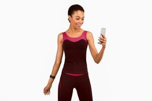 Fitness Application. Fit Afro Girl Using Smartphone Standing Over White Background. Studio Shot, Isolated photo