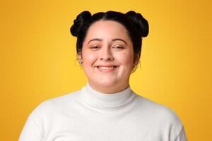 Body Positive. Cheerful Overweight Girl In White Turtleneck Sweater Smiling At Camera While Posing Over Yellow Background In Studio, Empty Space photo