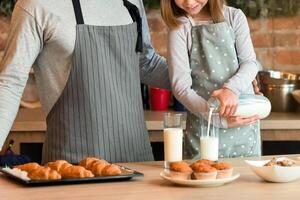 Happy young dad and little daughter enjoying homemade muffins and drinking milk, spending time together in kitchen, copy space photo