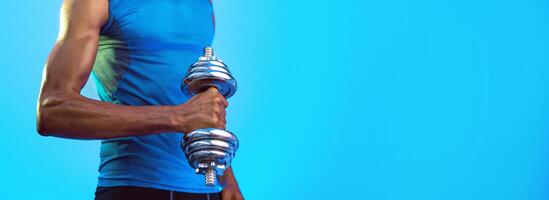 Unrecognizable African American Sporty Guy Exercising With Dumbbell On Blue Background In Studio. Selective Focus, Panorama photo