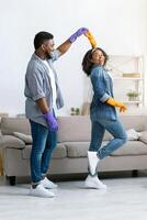 Loving African American Couple Dancing While Cleaning Flat Together, Having Fun At Home, Copy Space photo