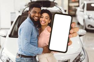 New Automobile. Cheerful Spouses Posing Hugging And Holding New Car Key In Dealership Showroom. photo