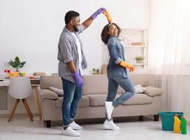 Loving African American Couple Dancing While Cleaning Flat Together, Having Fun At Home, Copy Space photo