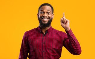 Great Idea Concept. Young Funny African American Man Pointing Finger Up. Excited Black Guy Got Solution To His Problem, Having Aha Moment, Isolated On Yellow Studio Background. Wow, Eureka photo