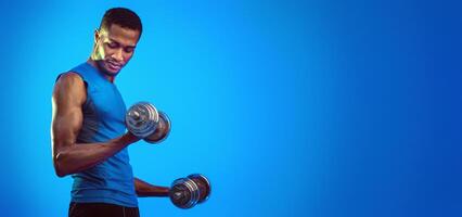 Strength Workout. Determined Fit Man Exercising With Dumbbells Pumping Bicep Muscles Over Blue Background. Studio Shot, Empty Space photo