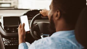 Car Navigation App. Unrecognizable Black Driver Guy Using Mobile Phone With Blank Screen Sitting In Automobile. Selective Focus, Mockup photo