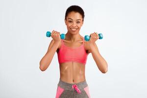 Workout. Smiling Afro Girl Doing Dumbbell Biceps Curl Exercise Over Pink Background. Studio Shot photo
