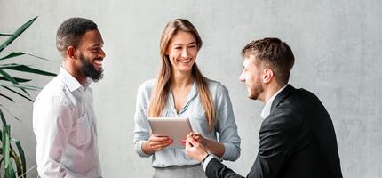 Happy Coworkers Talking Standing Near Desk Having Break At Work In Modern Office. Corporate Lifestyle Concept photo
