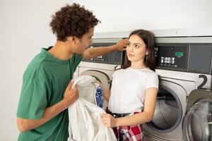A young man and woman engage in playful banter while doing laundry at a laundromat. The ambience is casual, with machines running in the background as they enjoy each other's company. photo