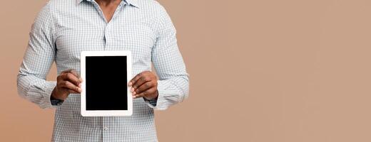 Modern digital tablet with blank screen in hands of african american man, empty space photo