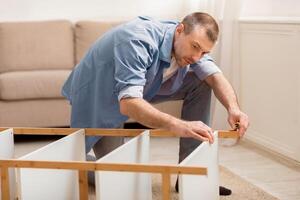 Furnishing Home. Mature Man Assembling Cabinet Installing New Furniture Using Self-Assembly Kit Indoors. Selective Focus photo