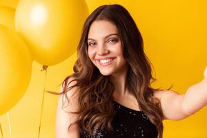 Lady Party. Selfie portrait of young pretty woman smiling at camera with big colorful balloons on background, capturing self-portrait at event photo