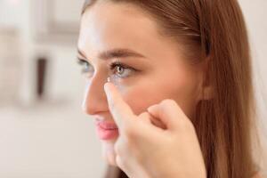 Contact Lens For Vision Concept. Close up side view portrait of smiling woman applying eye lens photo