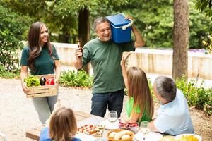 A cheerful group enjoys a picnic in the park, sharing food and drinks while engaging in lively conversation. They celebrate a sunny day surrounded by greenery and good company. photo