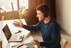 Freelance Networking. Man In Headphones Making Call Via Laptop Working Sitting In Modern Office. photo