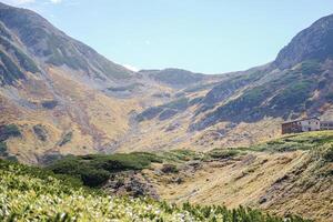 Murodo, Tateyama Kurobe Alpine Route, Japan, A scenic landscape featuring rolling mountains, lush greenery, and a serene sky photo