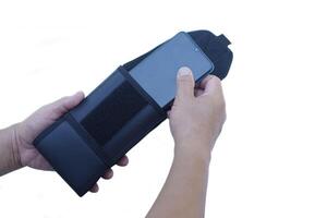 Close up man hands putting smartphone into bag, isolated on white background. Concept, accessory for containing mobile phone, waist belt vertical type. photo