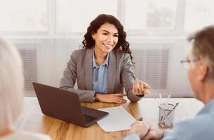 Expert. Senior couple sitting together at the desk and listening to their mexican financial advisor gesturing photo