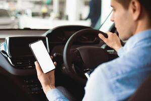 Smart Driving App. Man Using Smartphone Sitting In New Car Buying Vehicle In Auto Center. Selective Focus, Mock up photo