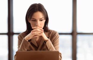 Problem Solving. Focused european businesswoman working on laptop at office, thinking about difficult task, copyspace photo