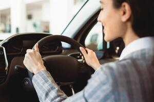 Driving Alone. Unrecognizable woman testing a car, rear view over the shoulder, selective focus on steering wheel photo